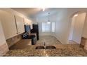 Modern kitchen featuring granite countertops, tile backsplash, and black appliances, with an adjacent dining area at 6784 W Gardenia Ave, Glendale, AZ 85303