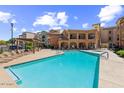 Large community pool with plenty of lounge chairs on the pool deck under a partly cloudy, blue sky at 14575 W Mountain View Blvd # 11212, Surprise, AZ 85374