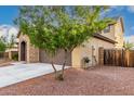 Side exterior view with a tree, stone accents, and a spacious driveway leading to a two-car garage at 21972 N 97Th Gln, Peoria, AZ 85383
