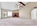 Spacious living room with a brick fireplace, vaulted ceiling, and a ceiling fan, great natural light at 2346 E Jasmine St, Mesa, AZ 85213