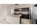 Eat-in kitchen boasts dark wood cabinetry, granite countertops, stainless appliances and a kitchen island at 29809 W Columbus Ave, Buckeye, AZ 85396