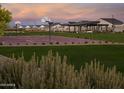 A community recreation area featuring a basketball court, lush green grass, picnic pavilion, and scenic sunset backdrop at 35524 N Tin Ct, San Tan Valley, AZ 85144