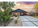 Charming single-story home with red brick and modern siding, well-manicured yard, and a concrete driveway with grass accents at 358 E Whitton Ave, Phoenix, AZ 85012