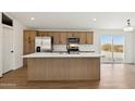 Modern kitchen featuring an island, stainless steel appliances, and wood-grain cabinetry at 51288 W Bluejay St, Maricopa, AZ 85139