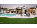 Inviting backyard oasis with a sparkling pool, lush lawn, and comfortable lounge seating for relaxation at 7100 N 47Th St, Paradise Valley, AZ 85253