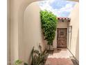 Charming entryway with a rustic wood door, red brick flooring, and lush greenery, creating a warm and inviting welcome at 7354 E San Miguel Ave, Scottsdale, AZ 85250