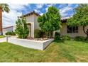 Landscaped front yard featuring lush green lawn, mature trees, and a charming stucco wall, enhancing the property's curb appeal at 7354 E San Miguel Ave, Scottsdale, AZ 85250