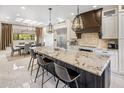 Bright, modern kitchen with a large center island, granite countertops, stainless steel appliances, and stylish pendant lighting at 7547 E Mary Sharon Dr, Scottsdale, AZ 85266