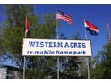 Sign at Western Acres RV-Mobile Home Park with welcoming flags in the background at 9913 E Main St # 40, Mesa, AZ 85207
