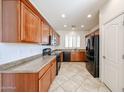 Efficient kitchen featuring wood cabinets, tile flooring, and modern appliances, all bathed in natural light at 12679 W Lowden Rd, Peoria, AZ 85383