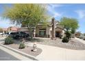 View of the front of the home, landscaped with mature shade trees, flowers, and rock at 16233 N 32Nd Ave, Phoenix, AZ 85053