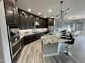 Modern kitchen featuring dark cabinetry, granite countertops, a spacious island, and stainless steel appliances at 32978 N 131St Dr, Peoria, AZ 85383