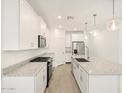 Bright kitchen featuring white cabinets, granite countertops, a kitchen island, and stainless steel appliances at 37069 W Prado St, Maricopa, AZ 85138