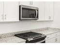 Close-up of a kitchen with white cabinets, granite countertops, and stainless steel appliances at 37069 W Prado St, Maricopa, AZ 85138