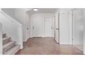 Bright foyer featuring neutral tile flooring, white walls, a staircase, and two entry doors at 11501 N Pablo St, El Mirage, AZ 85335