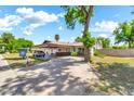 Long driveway leads to a home with a covered carport, turquoise doors, and a mature shade tree at 1451 E Brown Rd, Mesa, AZ 85203