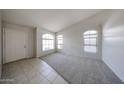 Bright living room featuring neutral carpet, white walls, tile entry, and arched windows at 15025 W Bottle Tree Ave, Surprise, AZ 85374