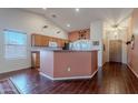 Open kitchen with wood cabinets, bar seating, and hardwood floors, perfect for entertaining guests at 1563 E Racine Dr, Casa Grande, AZ 85122
