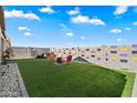 Spacious backyard featuring artificial grass, colorful block wall, and outdoor seating area at 1601 S 215Th Dr, Buckeye, AZ 85326