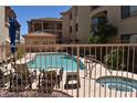 Community pool area featuring a clear blue pool, hot tub, lounge chairs, and a seating area, surrounded by a fence at 16631 E El Lago Blvd # 212, Fountain Hills, AZ 85268