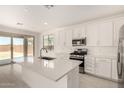 Kitchen with island, stainless appliances, white shaker cabinets, quartz countertops, and slider to covered patio at 18189 W Hess St, Goodyear, AZ 85338