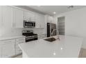 Modern kitchen with stainless steel appliances, white cabinets, and an island with a sink at 18189 W Hess St, Goodyear, AZ 85338