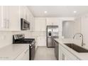 The kitchen features stainless steel appliances, white cabinets, quartz countertops and subway tile backsplash at 18189 W Hess St, Goodyear, AZ 85338