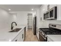Open kitchen showcases stainless steel appliances, white cabinets, modern fixtures, and a convenient pantry at 18204 W Hess St, Goodyear, AZ 85338