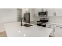 Modern kitchen featuring stainless steel appliances, sleek white cabinetry, and a spacious center island with a sink at 18204 W Hess St, Goodyear, AZ 85338
