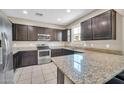Modern kitchen boasting stainless steel appliances, granite countertops, and dark wooden cabinets at 2049 N 77Th Dr, Phoenix, AZ 85035