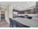 Stylish kitchen featuring dark cabinets, stainless steel appliances, and a granite countertop island at 2049 N 77Th Dr, Phoenix, AZ 85035