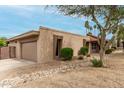Side view of a home with a tan exterior, desert landscaping and an attached garage at 3255 E Malapai Dr, Phoenix, AZ 85028