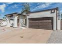 Single-story home featuring a large two-car garage, white stucco and brown trim exterior at 6701 W Monterey Way, Phoenix, AZ 85033