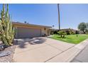 Single-story home featuring desert landscaping, a two-car garage and a large concrete driveway at 7615 E Tucson Rd, Scottsdale, AZ 85258