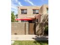 Inviting condo facade with a private patio featuring a stylish wood gate and red patio umbrellas at 8061 E Glenrosa Ave, Scottsdale, AZ 85251