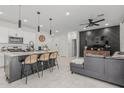 Open-concept living area with a kitchen island, pendant lighting, and a stylish accent wall at 8715 W Agora Ln, Tolleson, AZ 85353