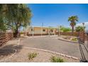 Well-maintained single-story home with a covered porch, desert landscaping, mature trees, and gravel grounds in a quiet neighborhood at 9710 E Baywood Ave, Mesa, AZ 85208