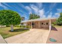 Charming home with a covered parking area, green lawn, and well manicured landscaping at 10860 W Cheryl Dr, Sun City, AZ 85351
