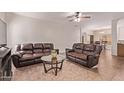 Spacious living room with two brown leather couches, glass table, ceiling fan, and tile floors at 12913 W Columbine Dr, El Mirage, AZ 85335