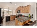 A well-lit kitchen is showcased with light wood cabinets and a granite countertop island and breakfast bar at 16222 W Augusta Ave, Litchfield Park, AZ 85340