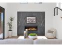 Contemporary living room features a sleek fireplace with stone surround, a plush armchair, and modern decor at 19550 N Grayhawk Dr # 1039, Scottsdale, AZ 85255