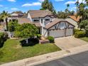 Eye-level shot of a well-maintained two-story home featuring a three-car garage, a manicured lawn, and mature trees at 19920 N 69Th Ave, Glendale, AZ 85308