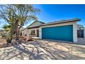 Well-kept house with desert landscaping and a large blue garage door providing ample parking and storage space at 2421 E Dragoon Ave, Mesa, AZ 85204