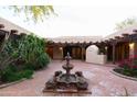Picturesque courtyard featuring a central fountain, lush greenery, and brick-paved flooring at 2430 N 56Th St, Phoenix, AZ 85008
