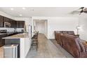 Modern kitchen with granite countertops, dark cabinets, and stainless steel appliances adjacent to living room at 24559 W Flores Dr, Buckeye, AZ 85326