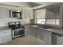 Well-lit kitchen featuring stainless steel appliances, window with blinds, and neutral countertops at 3738 W Danbury Dr, Glendale, AZ 85308
