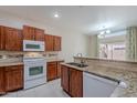 Bright kitchen featuring wooden cabinetry, white appliances, granite countertops and a stylish tile backsplash at 440 S Val Vista Dr # 11, Mesa, AZ 85204