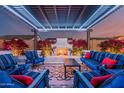 Outdoor covered patio with fireplace, pergola, blue sofas, and manicured plants at twilight at 8127 E June St, Mesa, AZ 85207
