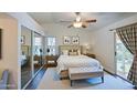 Bright bedroom with a ceiling fan, a light colored bed, mirrored closet doors, and access to the backyard at 9967 W Devonshire Ave, Phoenix, AZ 85037
