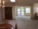Open-concept living room with neutral carpet, chandelier, and sliding doors to patio at 10428 W Camelot Cir, Sun City, AZ 85351